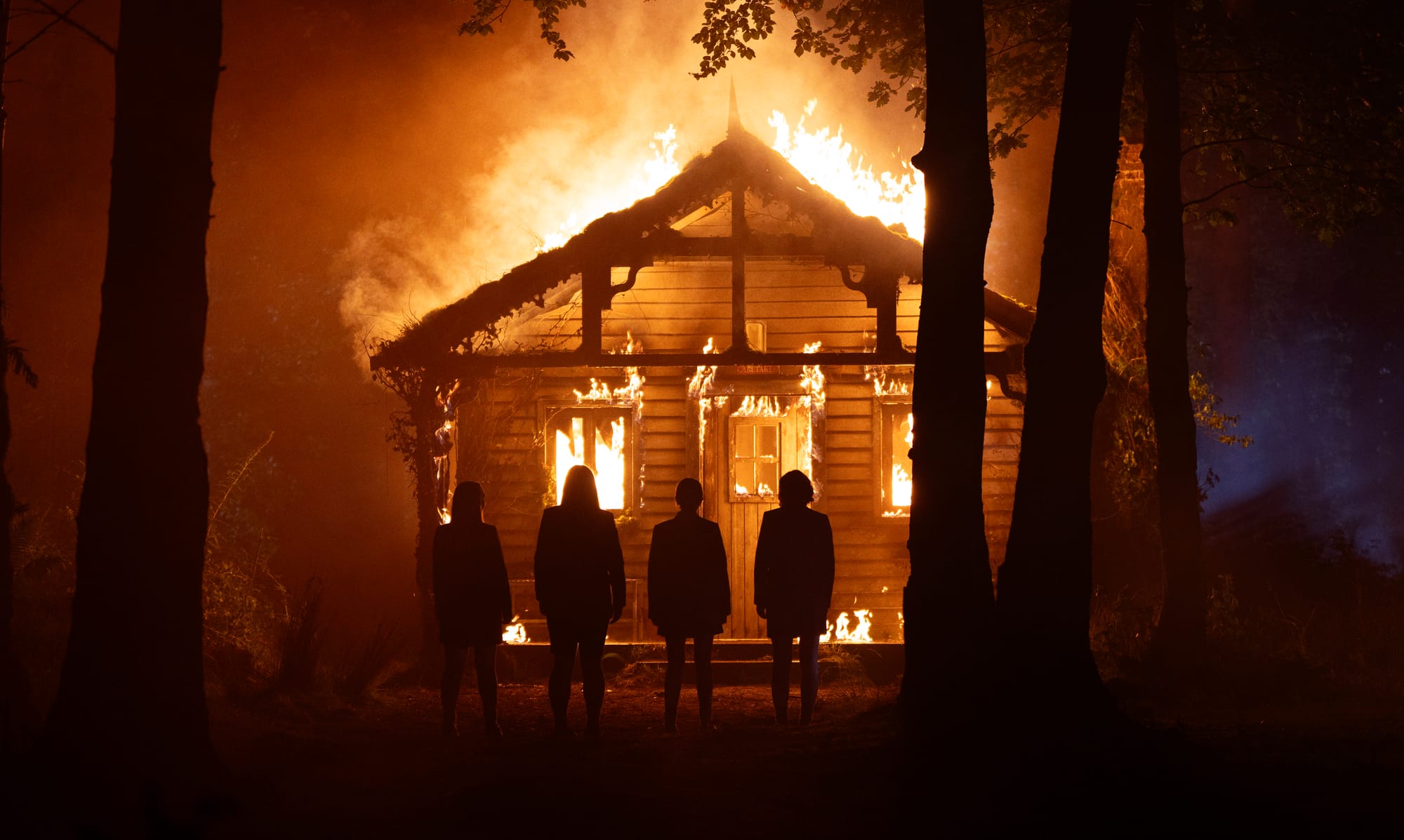 Four unidentified figures in front of a burning house in "How to Get to Heaven From Belfast"
