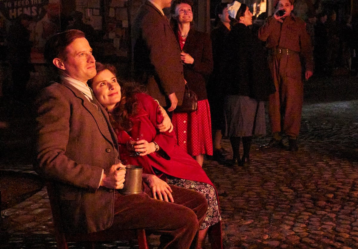 James and Helen Herriot snuggle by the bonfire in Darrowby Town Square as everyone celebrates the end of the war in Europe.