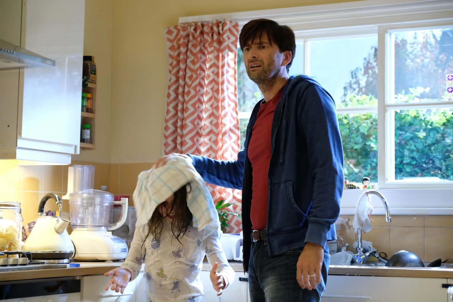 Simon (David Tennant) mops up Rosie (Miley Locke) after she's poured a carton of milk over her head.