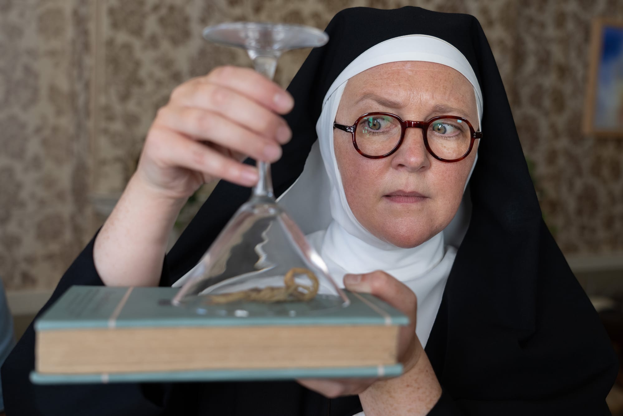Lorna Watson as Sister Boniface captures a scorpion under a glass in 'Sister Boniface Mysteries' Season 3