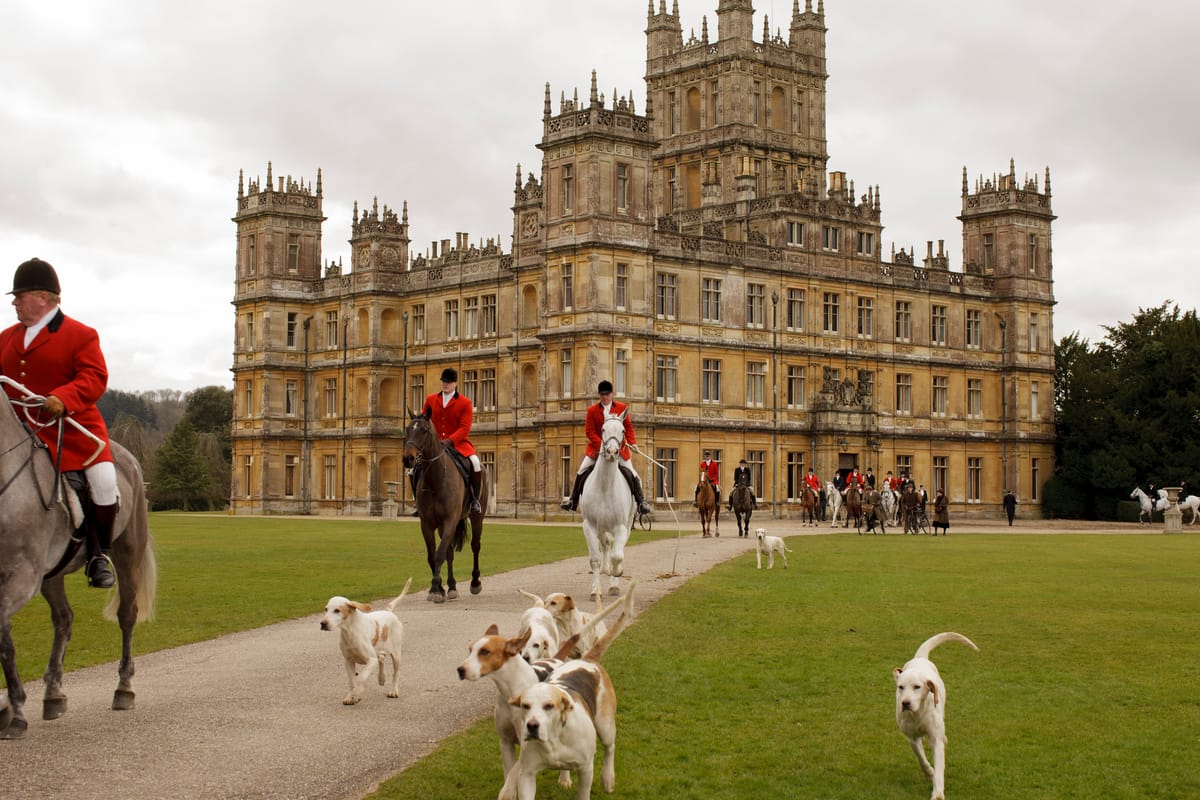 The hunt ride out on horseback with hounds with the Abbey in the background.